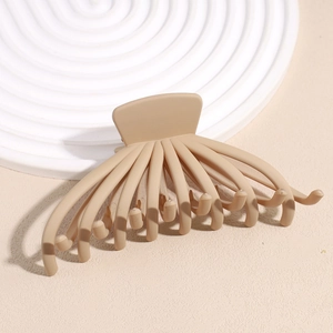 Close-up of a large matte beige octopus hair claw clip on a white textured board