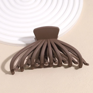 Detail view of large dark brown matte octopus hair claw clip on a textured display surface