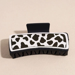 Detail view of square black claw clip with cow print pattern in premium faux leather finish