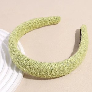 Détail d'un serre-tête tressé vert clair orné de paillettes argentées scintillantes