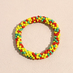 Close-up of vibrant woven beaded hair tie in red, yellow, and green ethnic style