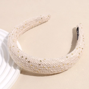 Détail du serre-tête en tweed crème avec paillettes dorées sur une monture épaisse
