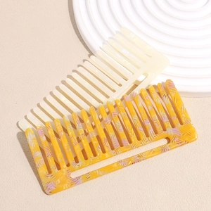 Détail de peignes à dents larges marbrés crème et orange sur un plateau décoratif