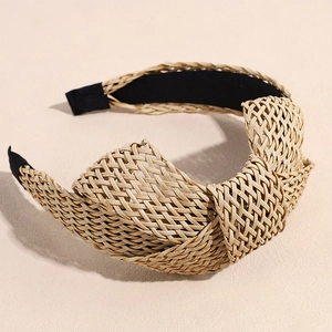 Detail of bohemian raffia headband featuring natural straw weaving and top knotted design
