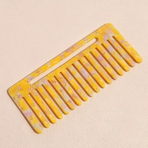 Détail d'un peigne à dents larges avec motif marbré jaune et violet en fini acétate