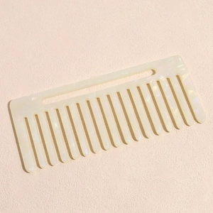 Détail macro du peigne à dents larges blanc crème avec motif marbré en acétate