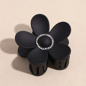 Detail view of a matte black floral hair claw clip featuring sparkling silver rhinestones