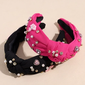 Detail von geknoteten Haarbändern mit rosa Schleifen, weißen Perlen und glitzernden Steinen
