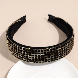 Detail view of black headband with gold rhinestones in a grid pattern on a white plate