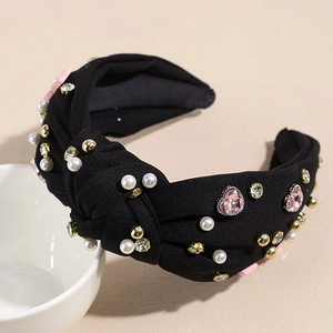Detailaufnahme von schwarzem Haarreif mit rosa Herzsteinen, Perlen und Glitzersteinen