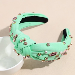 Detail eines mintgrünen geknoteten Stirnbands mit Perlen, Strass und Football-Anhängern