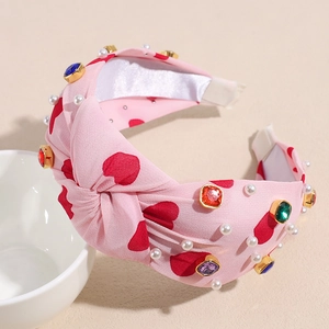 Close-up of pink heart pattern knotted headband with colorful rhinestones and pearls
