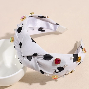 Detailed shot of white satin knotted headband with heart patterns and colorful rhinestones