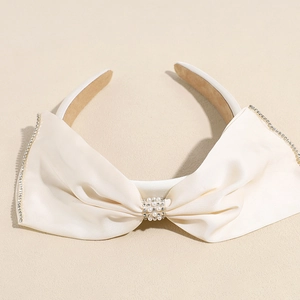 Détail d'un serre-tête élégant en satin crème avec perles et bords en strass fins