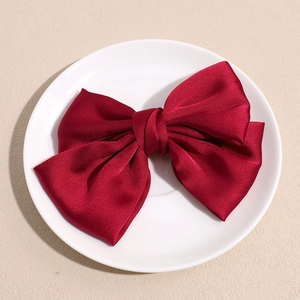 Détail d'un grand nœud à cheveux en satin rouge foncé avec un fini soyeux brillant
