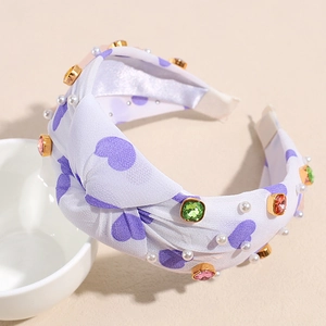 Detail of purple knotted headband featuring heart print, colorful crystals and white pearls
