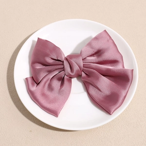 Vue détaillée d'une pince à cheveux nœud en satin rose poudré sur assiette céramique