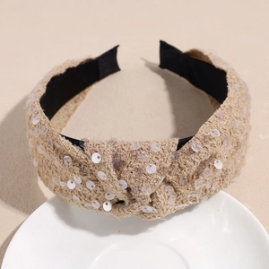Close-up of beige knitted headband with silver sequins and cross knot design detail