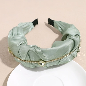 Details vom hellgrünen gefalteten Satin-Haarreif mit funkelnden Strassketten und Kristallen