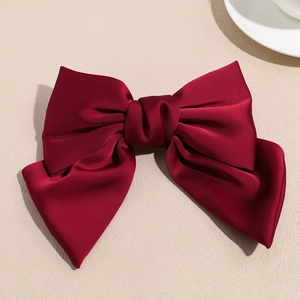 Detail of elegant wine red satin bow hair clip featuring a smooth and glossy fabric texture