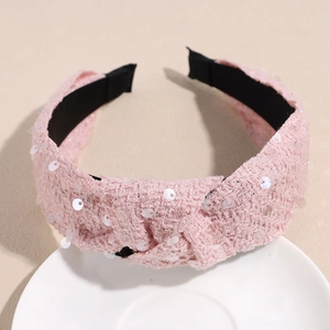 Detail of pink tweed headband with sequins and knot design on a white ceramic plate