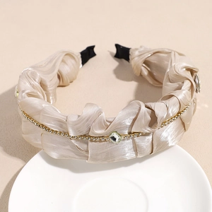 Detailansicht eines champagnerfarbenen Satin-Haarreifs mit Strasskette und zentralem Kristall