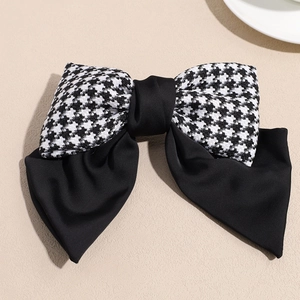 Macro shot of double-layered bow hair clip featuring classic houndstooth and black satin