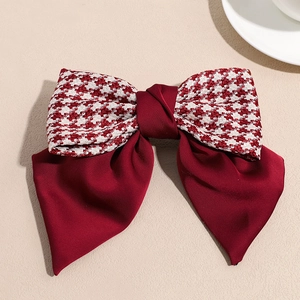 Detail of red satin bow hair clip with houndstooth fabric pattern and large layered design