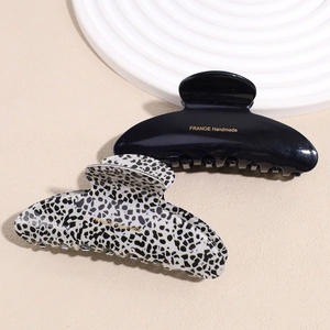 Elegant acetate hair claw clips in solid black and tortoiseshell pattern with gold label