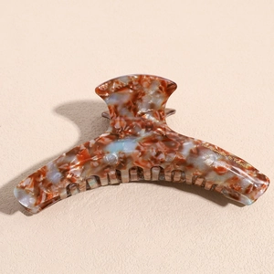 Detailed macro view of an amber marble acetate hair claw with gold handmade text