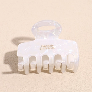 Detail view of pearlescent white hair claw clip with golden Barrette La France text