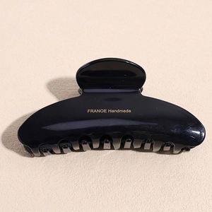 Detailed top view of large black acetate hair claw clip with gold Franoe branding