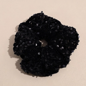 Vue détaillée d'un chouchou en velours noir orné de paillettes brillantes et de plis souples