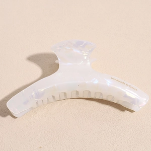 Macro view of handmade large acetate hair claw with white pearl finish and gold France logo