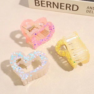 Star and heart-shaped claw clips in pink, yellow, and clear resin with star sequins