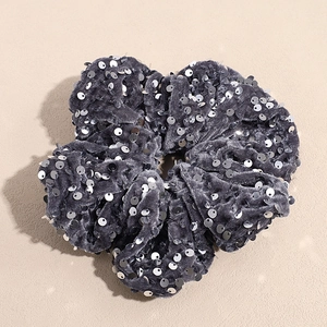 Vue détaillée du chouchou en velours gris avec des paillettes argentées brillantes et texture