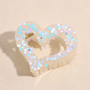 Detail of heart-shaped hair claw clip with star sequins and golden metal spring mechanism