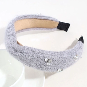 Detailansicht eines grauen Strick-Stirnbands mit Perlen und Strass auf weißem Grund