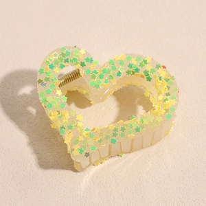 Detail of cream heart hair claw clip with vibrant green and yellow star sequins