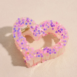 Detail of a large pink heart claw clip with colorful star sequins and durable metal spring