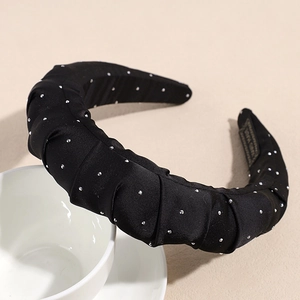Détail d'un serre-tête en soie plissée noire avec strass sur une tasse en céramique blanche