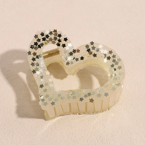 Macro shot of cream heart hair claw clip with gold and silver glitter star patterns
