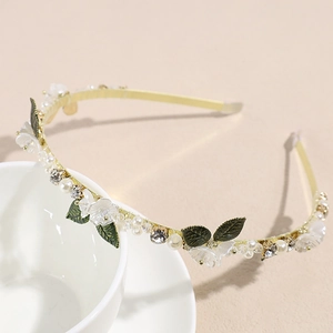 Détail d'un serre-tête floral avec perles, feuilles vertes et cristaux sur une tasse
