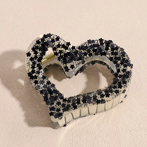 Macro shot of heart-shaped acrylic hair claw with black stars and shiny sequins