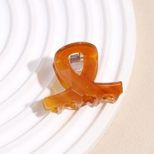 Close-up of tortoise shell pattern acetate hair claw clip with cross ribbon design