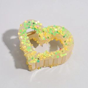 Detail of heart hair claw clip with yellow and green sequins and golden spring