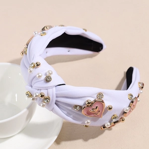 Détail du serre-tête noué blanc orné de perles, strass et cœurs en émail rose