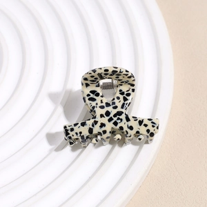 Detailed close-up of a small spotted acetate hair claw clip with cross design details