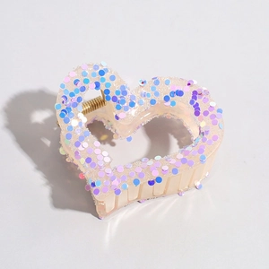 Detail of cream heart hair claw clip with colorful sequins and golden spring