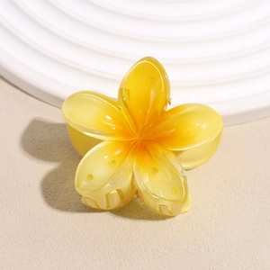 Macro detail of a yellow gradient frangipani hair claw clip on a stylish wavy tray